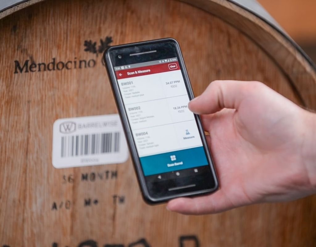 Image of smartphone with BarrelWise app on screen scanning a wine barrel